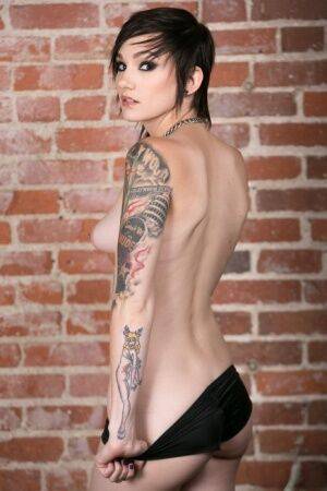 Punk girl Nikki Hearts frees her tattooed body of clothes afore a brick wall on picsofsex.com