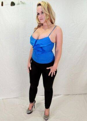 Middle-aged blonde Dee Siren displays her ample cleavage in black leggings on picsofsex.com