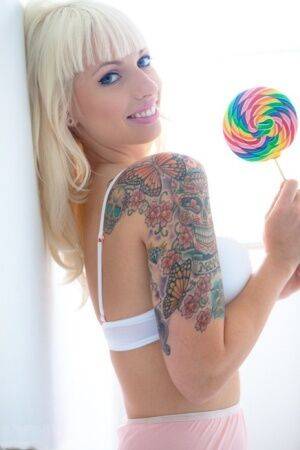 Tattooed blonde Lynn Pops strikes great poses with a lollipop in hand on picsofsex.com