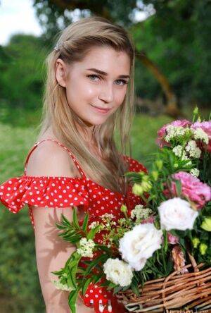 Young blonde Christine Cardo gets naked in a hilly field while picking flowers on picsofsex.com