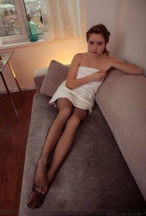 Beautiful teen Lu removes mesh stockings to get completely naked on a couch on picsofsex.com