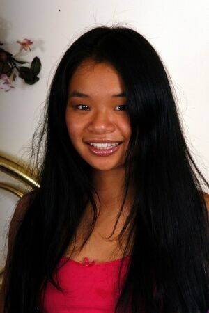 Asian teen with long hair flashes cotton panties before masturbating on a bed on picsofsex.com