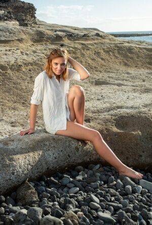 Pretty teen Oxana Chic disrobes for a nude modelling gig on a beach on picsofsex.com