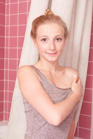 Fair skinned teen wears her hair up while getting wet during a shower on picsofsex.com