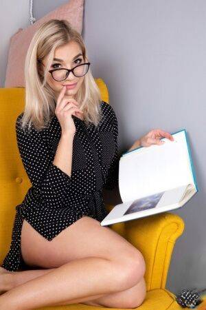 Geeky blonde Amelia undresses on a chair before playing with her shaved pussy on picsofsex.com