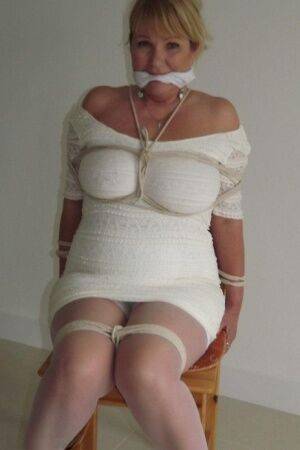 Blonde female is cleaved gagged and tied with rope in a number of dresses on picsofsex.com