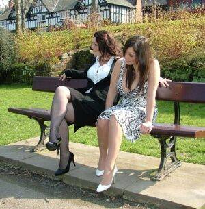 Clothed females admire each other high heeled shoes on a park bench on picsofsex.com