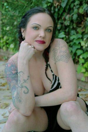 Tattooed girl with dark hair Zoe frees big naturals from bikini top by a pool on picsofsex.com