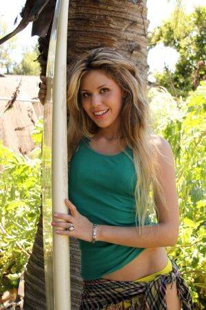 Cute blonde Kira takes off her clothes under a tree for her first nudes on picsofsex.com