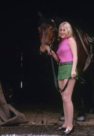 Blonde female reveals thigh and ass while mounting her horse in a short skirt on picsofsex.com