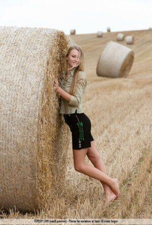 Beautiful blonde teen Carisha strips naked next to a round bale of hay on picsofsex.com