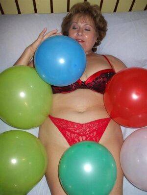 Older lady Busty Bliss plays with balloons before uncupping her natural tits on picsofsex.com