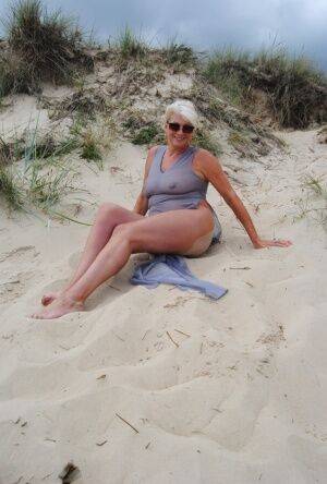 Mature platinum blonde Dimonty models at the beach in see through clothing on picsofsex.com