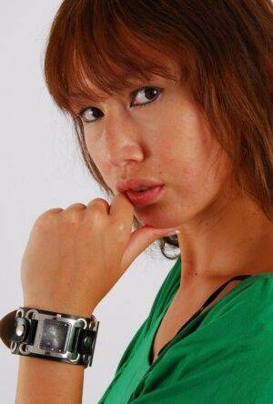 Redheaded Asian girl Evita models a Guess style cuff watch during SFW action on picsofsex.com