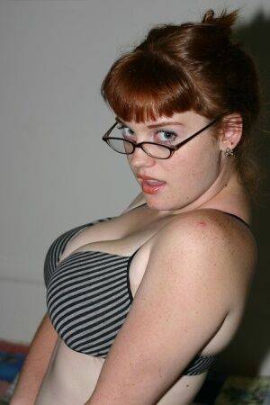 Redhead amateur Sawyer cups her natural breasts before removing her glasses on picsofsex.com