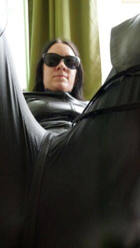 Dark haired amateur models a leather catsuit while wearing dark sunglasses on picsofsex.com