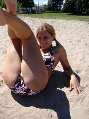 Blonde teen Karen models a bikini while on a patch of sand on picsofsex.com