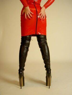 Blonde chick Avengelique models a red latex dress in thigh-high stiletto boots on picsofsex.com