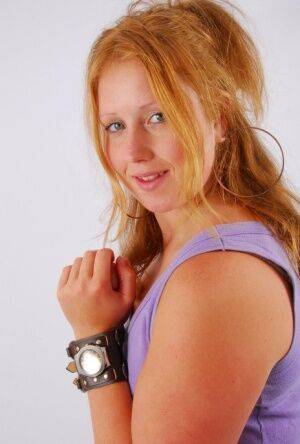 Natural redhead models a large cuff watch in a tank top and faded jeans on picsofsex.com