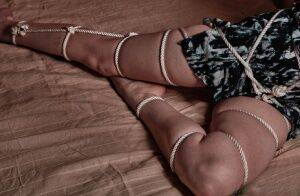 Slender female models with ropes wrapped around dress and naked pussy on picsofsex.com