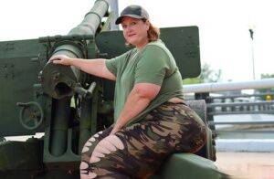 Obese amateur Goddess Pear models for a SFW shoot on an artillery gun in camo on picsofsex.com