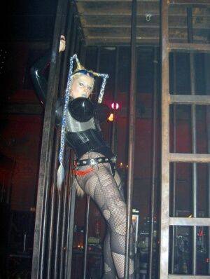 Caucasian female Dark Wing models latex apparel while in a watery cage on picsofsex.com