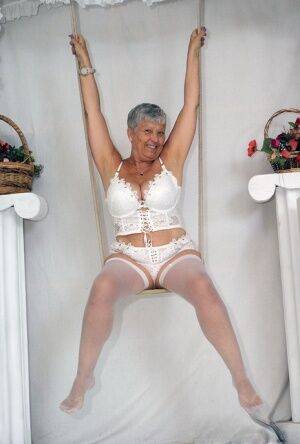 Short haired oma Savana models all white lingerie and hosiery on a swing on picsofsex.com