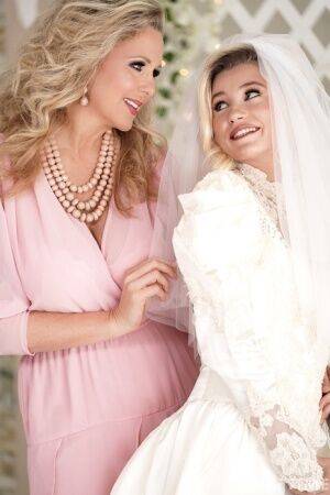 Carolina Sweets is affixed with a garter before a lesbian wedding to Julia Ann on picsofsex.com