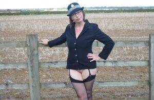 Mature policewoman Barby Slut removes her uniform against a fence at a farm on picsofsex.com