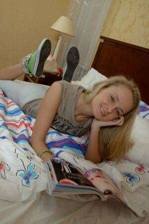 Cute blonde Rita reads a magazine in bed when a young man steps into the room on picsofsex.com