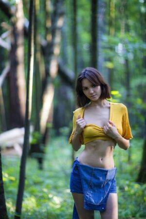 Skinny brunette Lara Masier gets completely naked in a mature forest on picsofsex.com