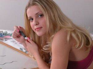 Young looking blonde Karen rubs lotion into her body in a bra and thong on picsofsex.com