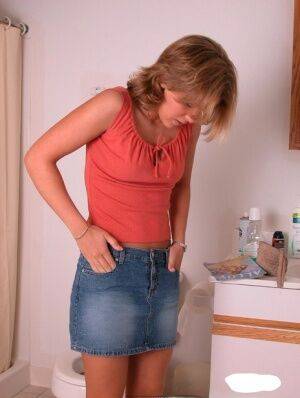 Amateur girl Karen hikes her denim skirt in the bathroom to expose her panties on picsofsex.com