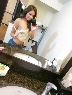 Sassy brunette stripping in front of the mirror and making selfies on picsofsex.com