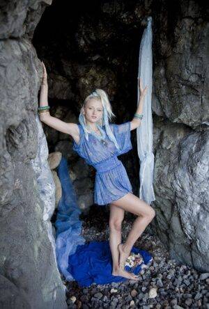 Young looking blonde Nika N finger fucks in a cave before blowing a kiss on picsofsex.com