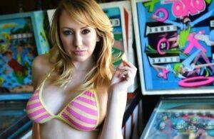 Brett Rossi fingers her pussy in striped OTK socks atop pinball machine on picsofsex.com