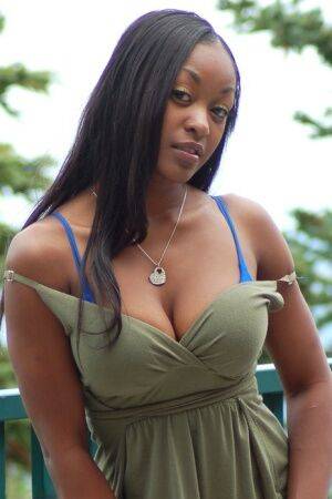 Ebony amateur Amber releases her big tits from a long dress on a balcony on picsofsex.com