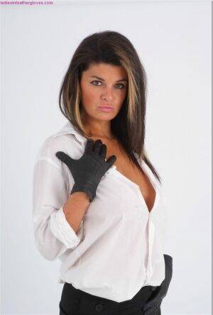 Clothed woman Claire lets a breasts escape a white shirt in leather gloves on picsofsex.com