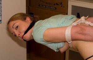 White girl is tied up and cuffed while ball gagged with pants pulled down on picsofsex.com