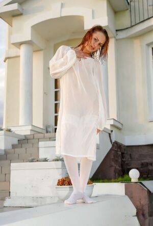Barely legal redhead Alisabelle poses nude in white stockings outside a house on picsofsex.com