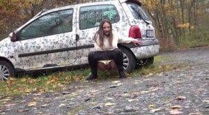 White girl Nicolette Noir takes a piss beside a parked car in a wooded setting on picsofsex.com