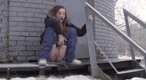 White girl pulls down her jeans to pee in the snow behind a building on picsofsex.com