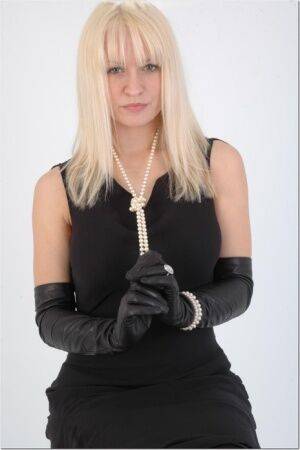 Natural blonde exposes some thigh while wearing long leather gloves on picsofsex.com