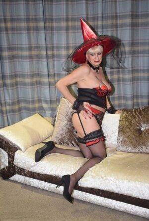 Older blonde removes a red velvet dress pose nude in a witch's hat and hosiery on picsofsex.com