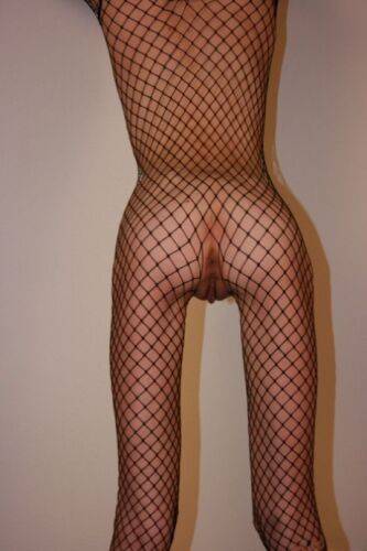 Solo model with a shaved head poses in a fishnet bodystocking on picsofsex.com