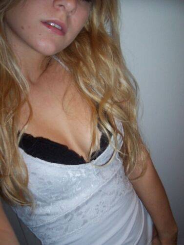 Blonde amateur Kylie takes mirror selfies while disrobing to her bra and thong on picsofsex.com