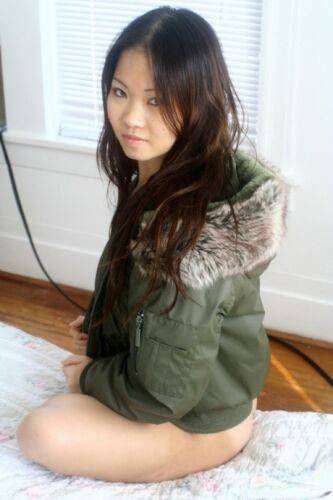 Asian amateur Grace removes a winter coat to model a thong during SFW action on picsofsex.com