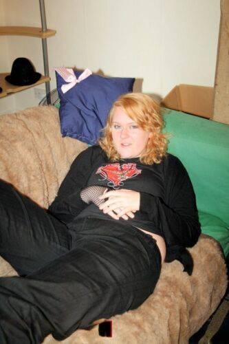 Redheaded fatty strips her sweatshirt and shows her cleavage in a black bra on picsofsex.com