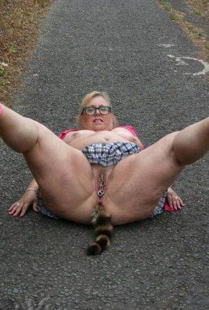 Fat UKwoman Lexie Cummings walks a path sporting a raccoon tail butt plug on picsofsex.com