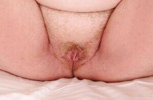 Mature plumper with huge saggy jugs and hairy cooter posing on the bed on picsofsex.com